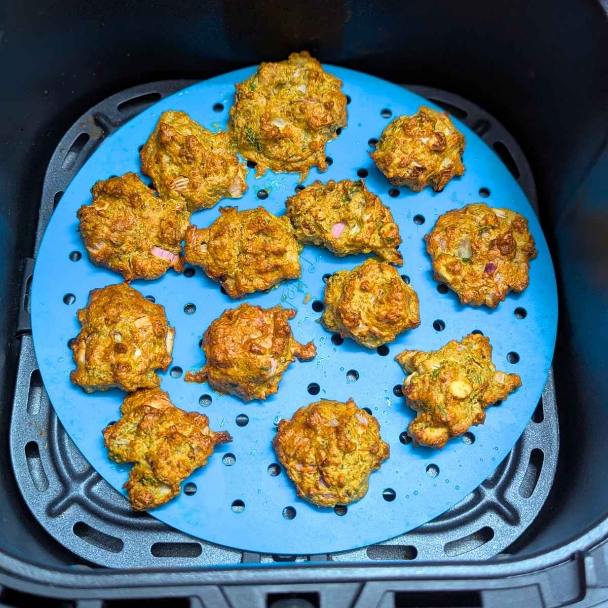 sprouted moong pakode in air fryer basket after air frying.