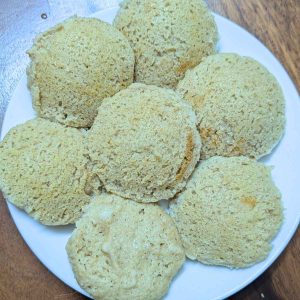 7 idlis after steaming on a white plate.