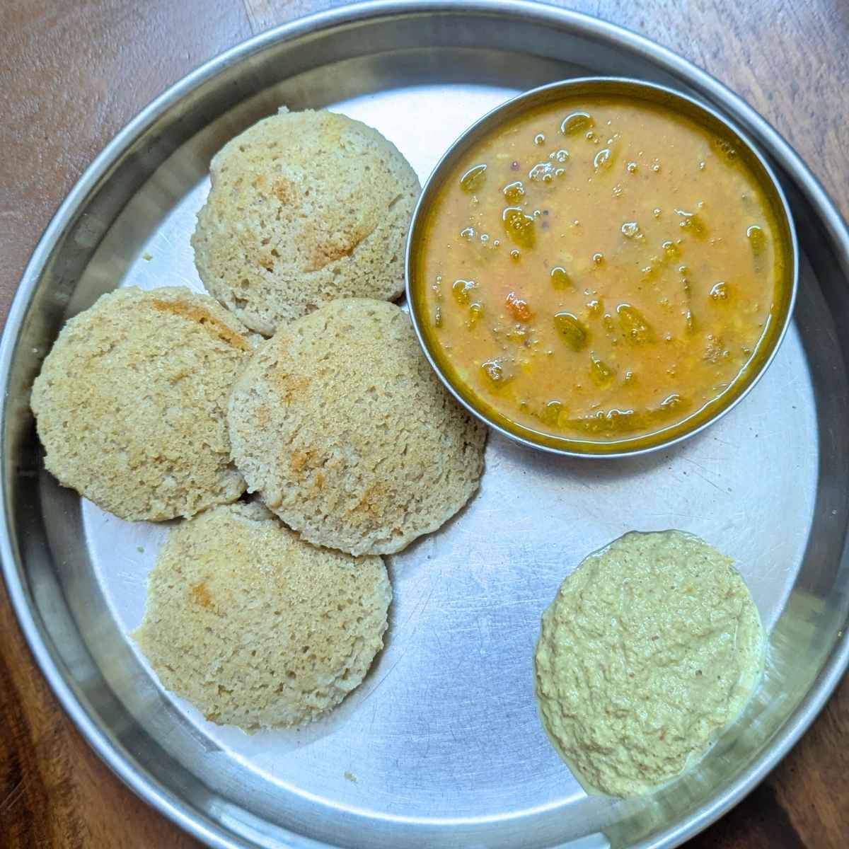 4 quinoa idlis with sambar and chutney on a plate.