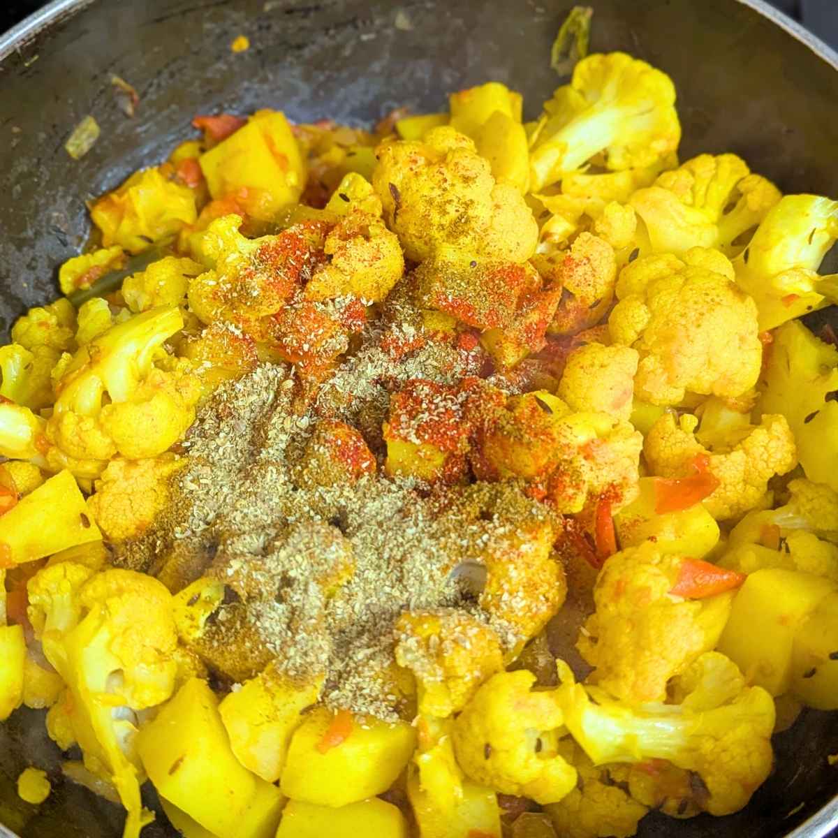 aloo gobhi with spice powders in a pan