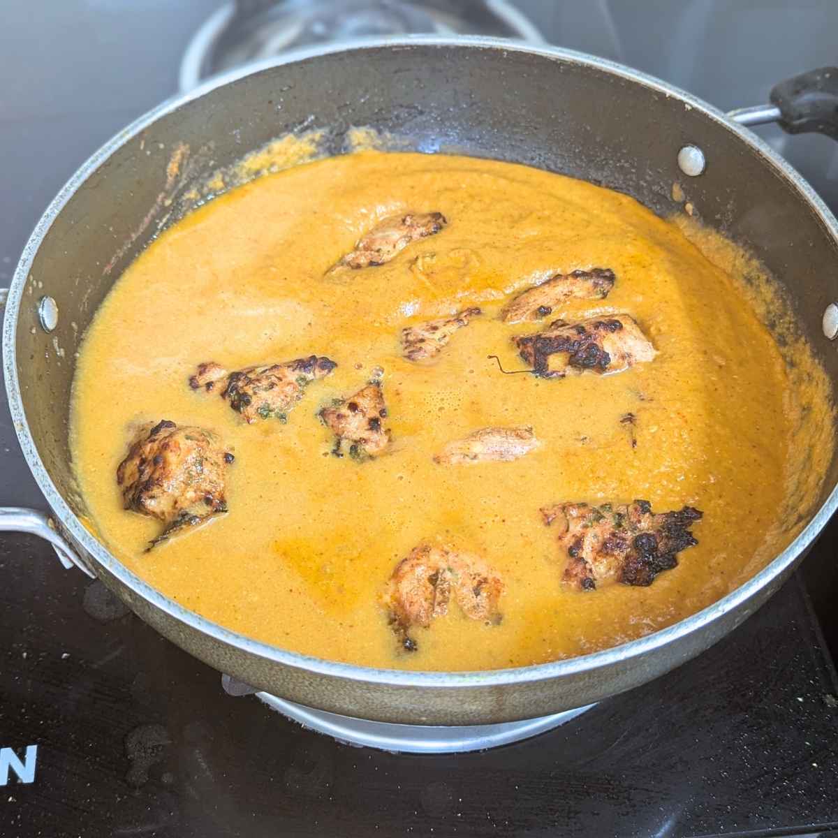 Chicken tikka added to the curry in a pan
