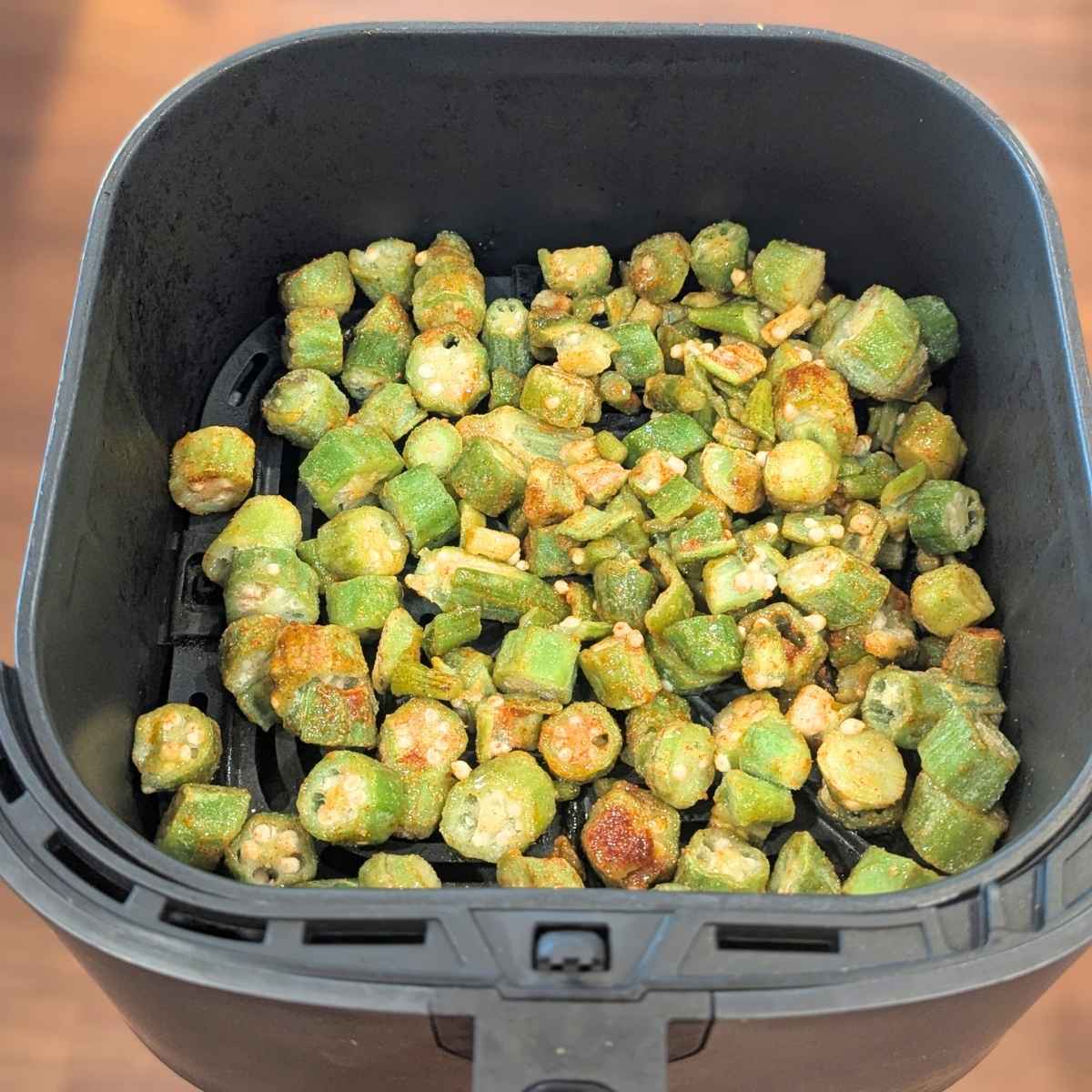 seasoned frozen okra in an air fryer basket.