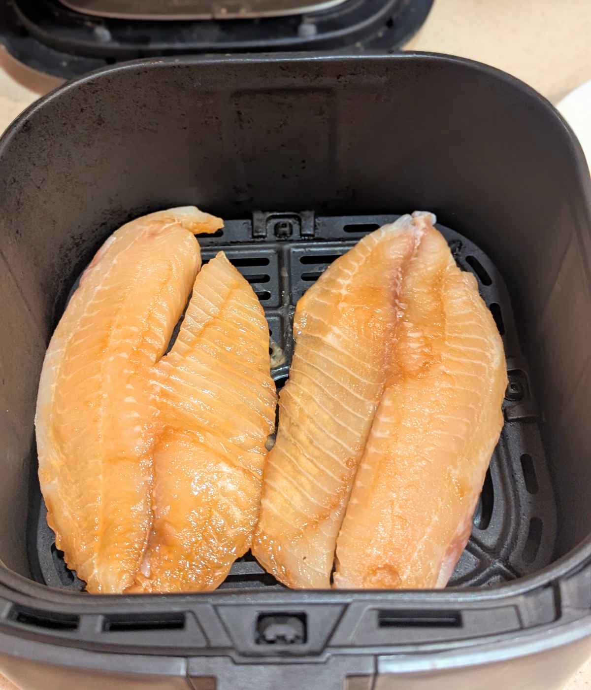 Tilapia fillets brushed with Teriyaki sauce and placed in air fryer basket
