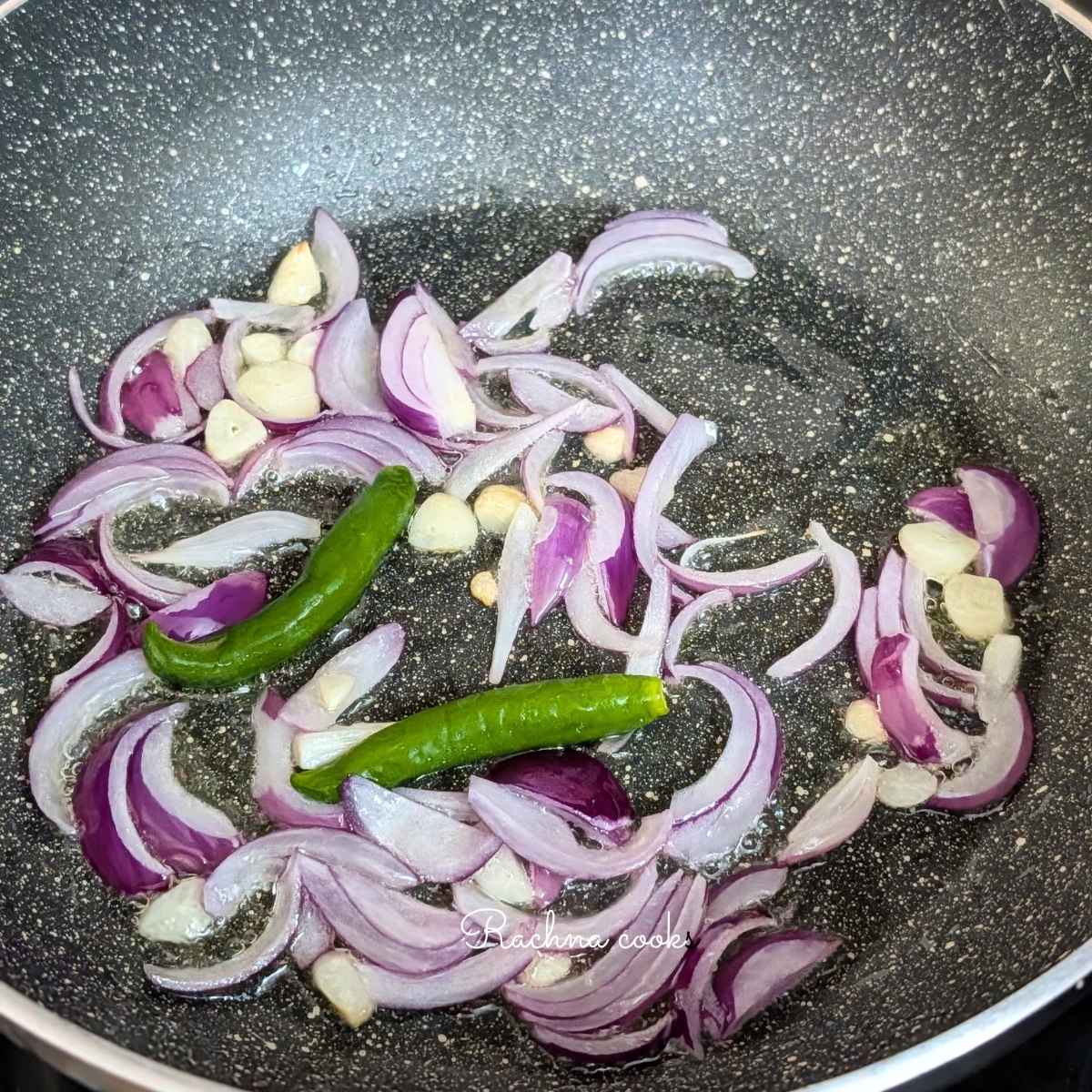 Sliced onion, garlic and green chillies added to oil in a pan