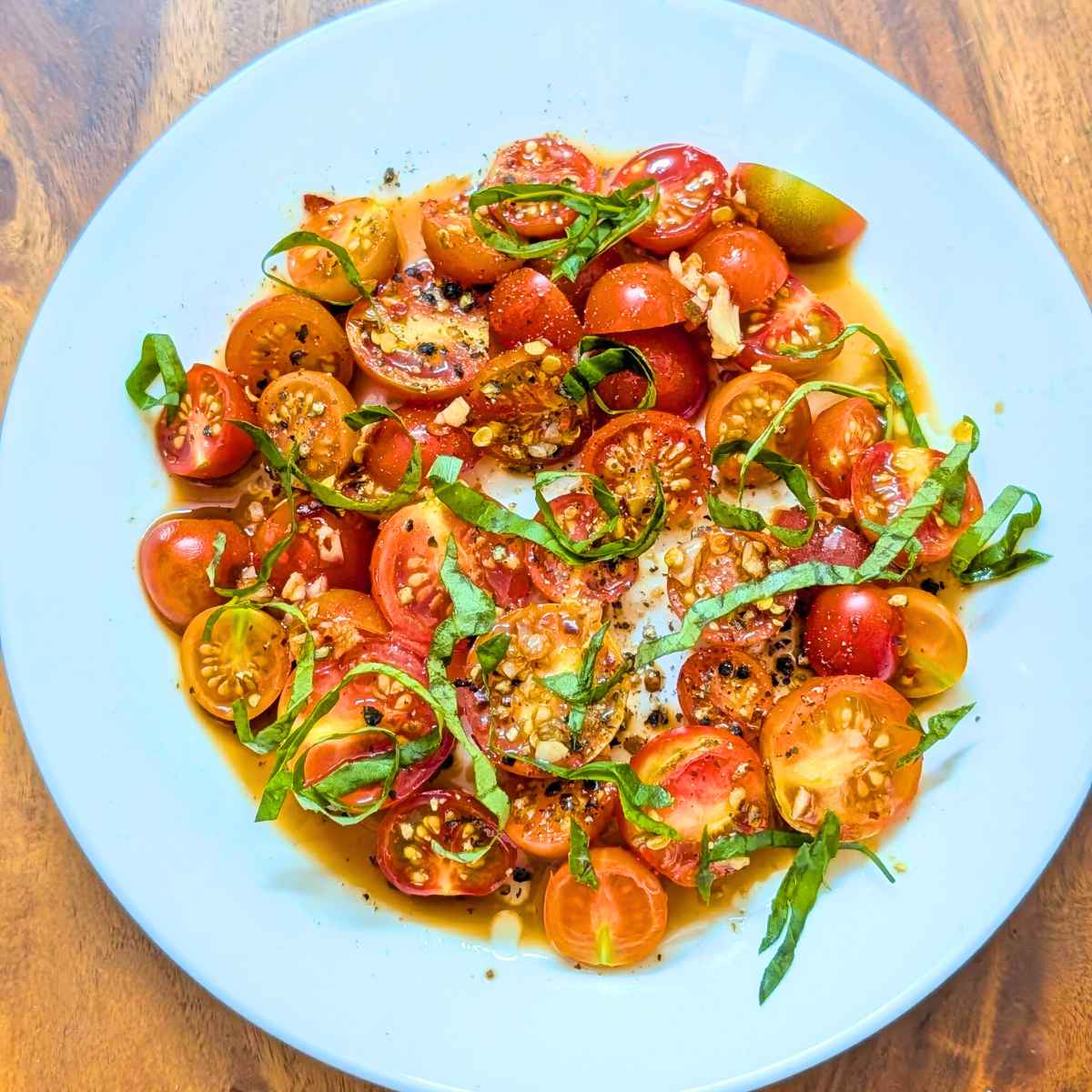 Basil and cheery tomato salad on a white plate