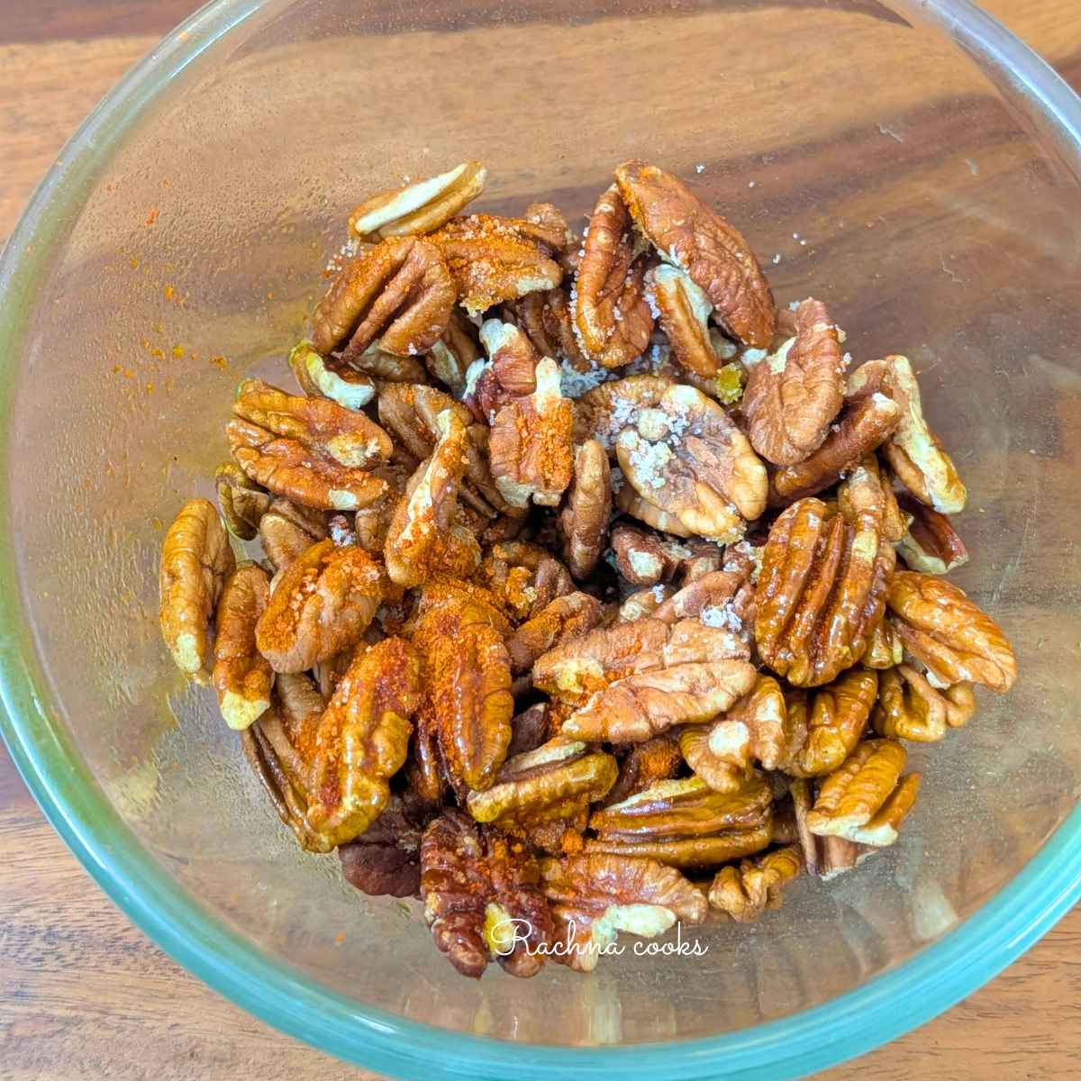 Seasonings and salt sprinkled on pecans in a bowl