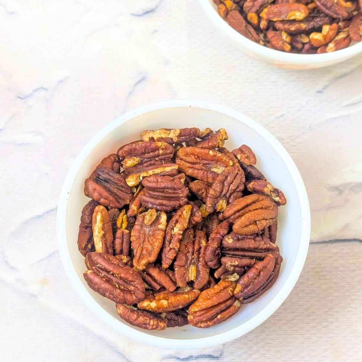 Two bowls of toasted pecans visible on a white background