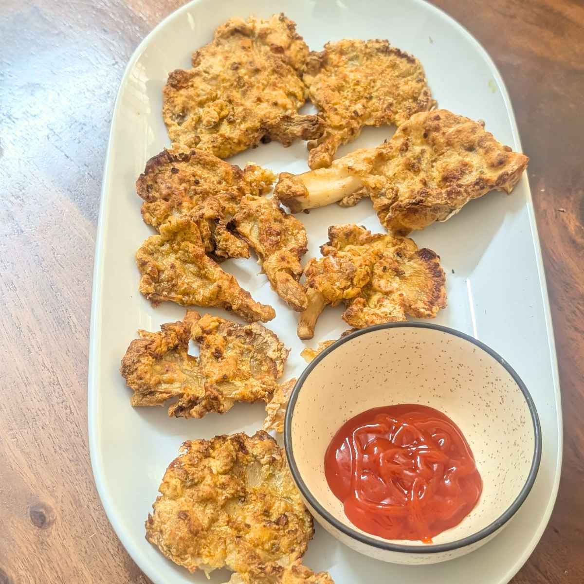 Oyster mushrooms after air frying on a plate with dip