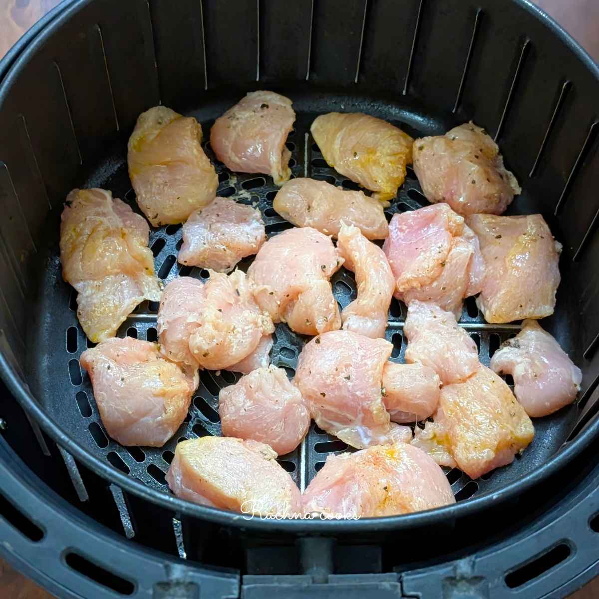 Coated chicken bites placed in air fryer basket for air frying