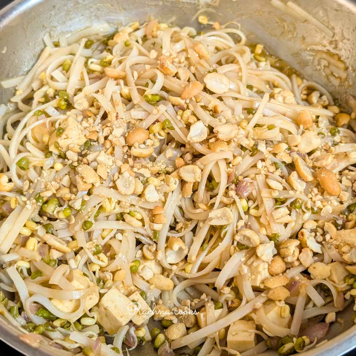 After tossing with sauce, pad thai noodles with tofu, bean sprouts and peanuts in a large wok