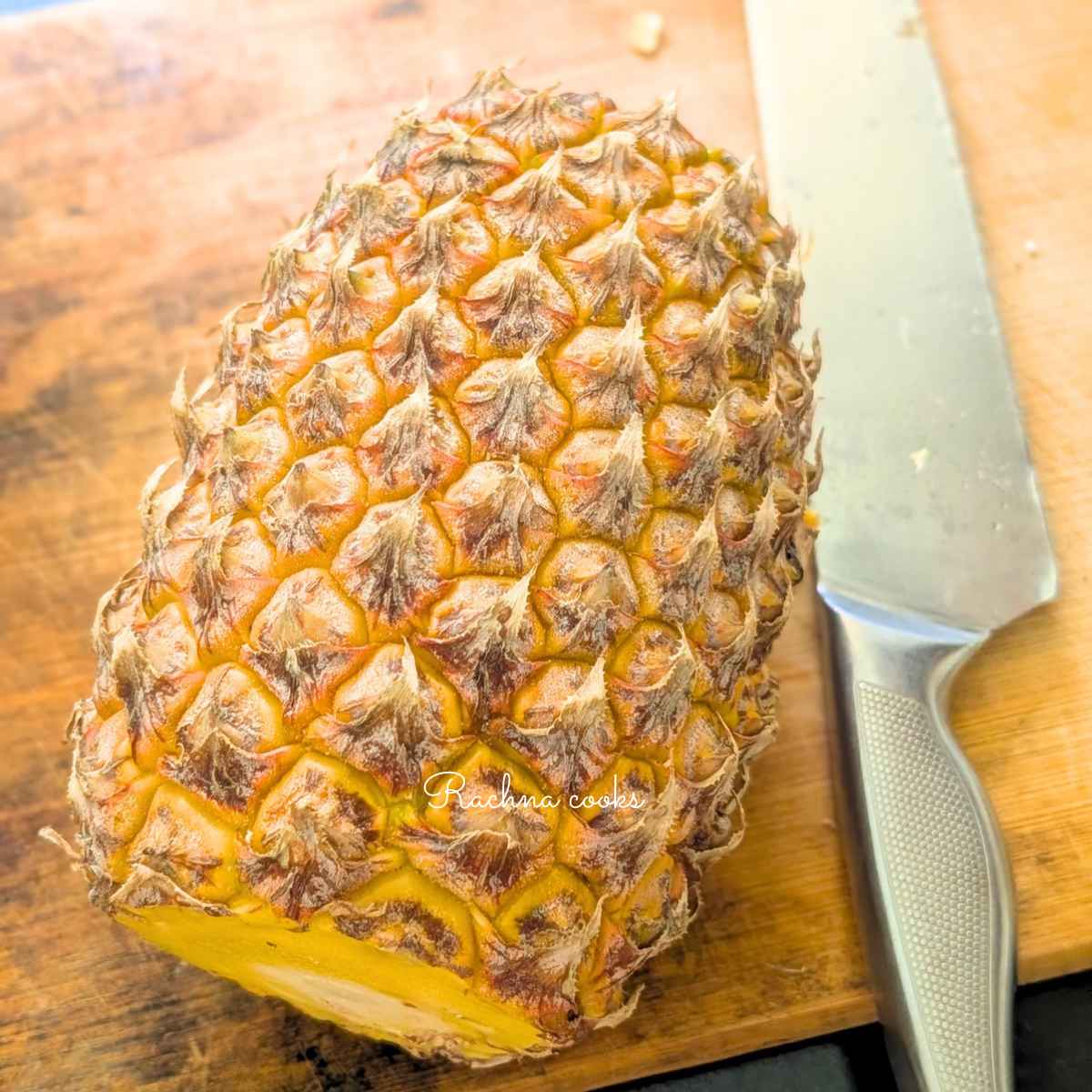 Whole pineapple with its crown cut off on a chopping board